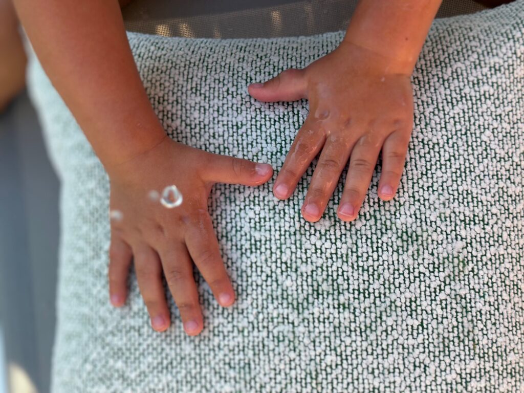 Dłonie dziecka na tkaninie outdoor FABB z technologią waterfree™ – woda pozostaje na powierzchni materiału dzięki właściwościom hydrofobowym.